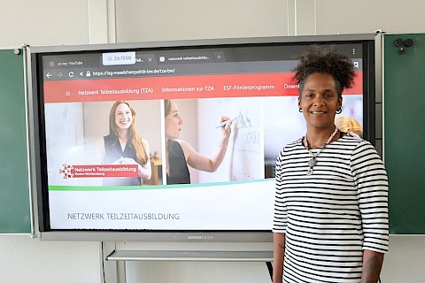 Junge Frau steht vor einer digitalen Tafel. Sie macht eine Teilzeitausbildung zur Erzieherin