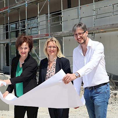 Die Vorständinnen der Stiftung Großheppacher Schwesternschaft stehen mit dem Architekten Johannes Michel vor einem Gebäude, das in Bau ist, mit einem Plan in der Hand.