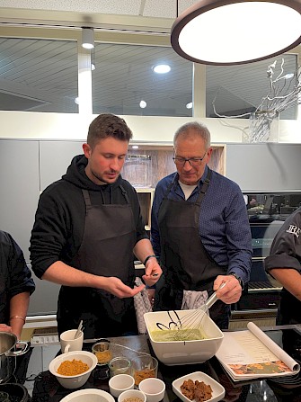 Zwei Männer stehen am Herd und kochen