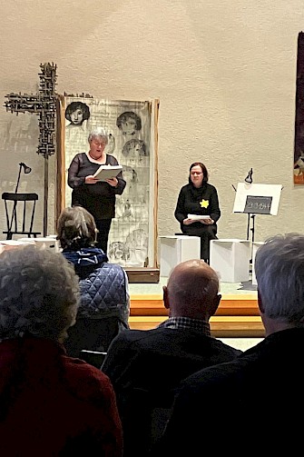 2 Frauen, eine sitzt und eine steht und liest aus den Briefen von Ilse Weber vor