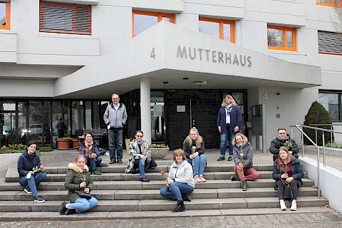 Nach der bestandenen Prüfung sitzen die Absolventen auf der Treppe vor dem Mutterhaus. Sie sind nun staatlich geprüfte Altenpfleger*innen